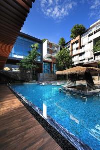 Ban KohongRichmann Resort Hotel Hatyai的一个带椅子和草伞的游泳池
