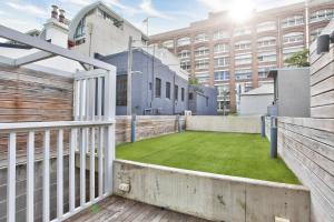 悉尼Astounding 3 Bedroom House Surry Hills 2 E-Bikes Included的大楼前带绿色草坪的阳台