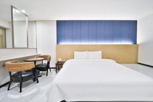 釜山Calm Rest Hotel Busan Sasang的卧室配有一张床和一张桌子及椅子