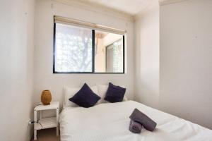 悉尼Cozy 2 Bedroom Apartment Surry Hills的一间卧室配有一张带蓝色枕头的床和一扇窗户。