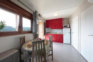 扎马亚Camping & Bungalows Zumaia的厨房配有红色橱柜和桌椅