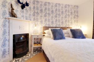 汤布里奇Pass the Keys Cute flat in Tonbridge的一间卧室配有床和壁炉,拥有蓝色和白色的壁纸