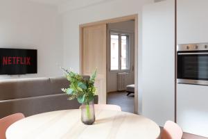 梅莱尼亚诺New Exclusive Melegnano Apartments- Near train station的客厅配有白色的桌子和花瓶