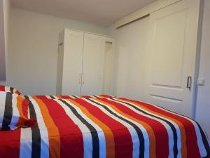 滨海韦克Modern zomerhuis voor 4 personen的床上有条纹的彩色毯子