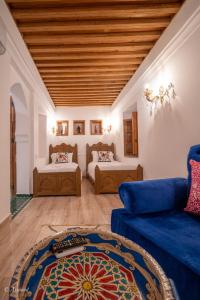 舍夫沙万Riad Dar Chama的客厅配有两张床和蓝色的沙发