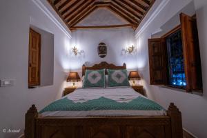 舍夫沙万Riad Dar Chama的一间卧室配有一张带两盏灯的床和两扇窗户。