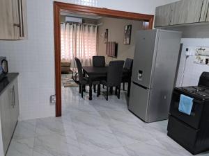 卢萨卡Edmut Apartments的厨房以及带桌子和冰箱的用餐室