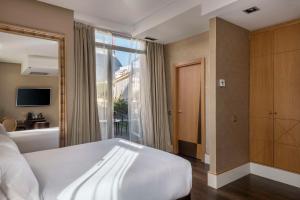 马德里马德里普拉多大道NH精品酒店的卧室设有一张白色大床和一扇窗户。