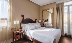 马德里马德里普拉多大道NH精品酒店的卧室配有一张白色大床和镜子