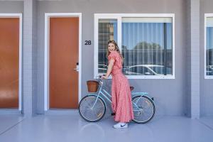阿德莱德HotelMOTEL Adelaide的一名年轻女孩站在自行车旁边