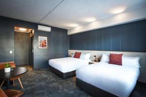 阿德莱德HotelMOTEL Adelaide的酒店客房设有两张床和一张桌子。