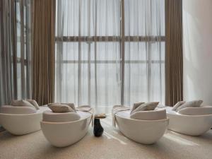 迪拜SO/ Uptown Dubai的带大窗户的客房内的3把白色椅子