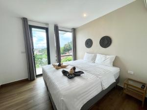 卡塔海滩Baan Saint-Tropez Seaview Villas Kata Beach的卧室配有带鞋的大型白色床
