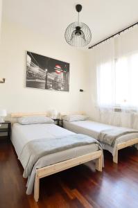 比萨Il Villino di Monic的配有白色墙壁和木地板的客房内的两张床