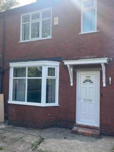 曼彻斯特Newly Renovated 3- Bed house in Prestwich的砖屋,有白色的门和窗户