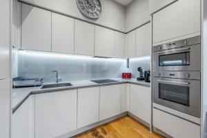 伦敦Large Modern One Bedroom Apartment (nearly 800 ft)的厨房配有白色橱柜和墙上的时钟