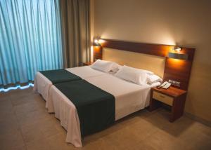贝尼多姆德鲁斯四星级高级酒店的一张大床,位于酒店客房内,配有电话