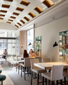 马德里圣多明戈酒店的坐在餐厅桌子旁的人,餐厅拥有格子天花板