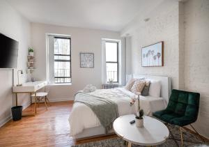 纽约Beautiful Studio Apartment At East Side的白色卧室,配有床和绿色椅子