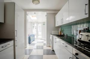 伦敦London comfy doubles的厨房配有白色橱柜和 ⁇ 格地板