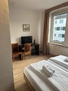 杜塞尔多夫Hotel Sonnenschein nähe Messe und Flughafen的配有一张床、一张书桌和一扇窗户的酒店客房