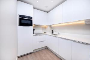 豪士罗New Modern 1 Bed Flat Great Location Piccadilly Line的白色的厨房配有白色橱柜和水槽