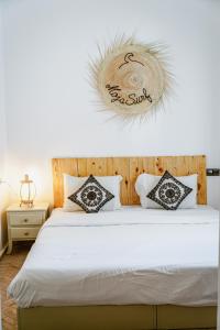 Tamraght Ou FellaDar Sultana Guesthouse Surf Morocco的一张带枕头的白色床和上面的标志