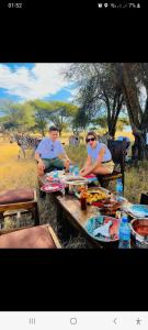 Boma la NgombeRainbow house的两人坐在斑马前的野餐桌上