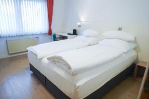 菲尔恩海姆AP Hotel Viernheim Mannheim am Kapellenberg的卧室配有一张带白色床单和枕头的大床。