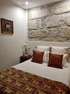 马托西纽什Honey House的卧室配有白色的床铺和石墙
