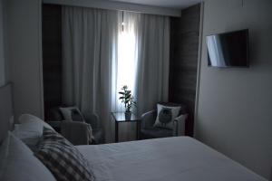 普韦布拉桑纳比亚维多利亚酒店的一间卧室配有一张床、两把椅子和一个窗户