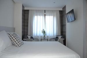 普韦布拉桑纳比亚维多利亚酒店的卧室设有一张白色大床和一扇窗户。