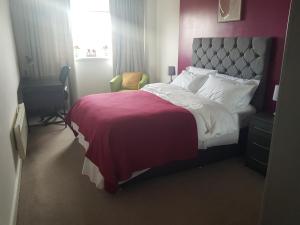 达德利Stunning 1-Bed Apartment in Brierley Hill的一间卧室配有一张带红色毯子的床和一张书桌