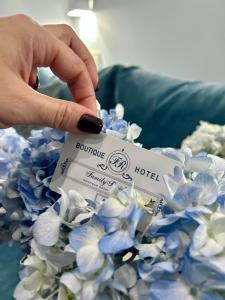利沃夫Family Residence Boutique Hotel的持有酒店卡的人,靠近蓝色的花朵
