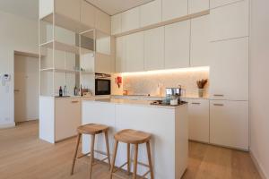 波尔图Mouzinho 32的厨房配有白色橱柜和2个酒吧凳