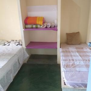 伊列乌斯Casa de Praia的小房间设有两张床,并铺有绿色地板。