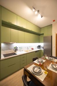 纳夫普利翁AKAKIA VILLA NAFPLIO的厨房配有绿色橱柜和木桌