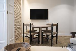 塞维利亚Luxury, Art and Deco apt para 4pax cerca de Plaza de España的餐桌、椅子和墙上的电视