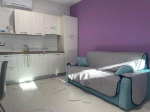 蒙多维Le Ghie的一间设有一张床的客房和一间带紫色墙壁的厨房