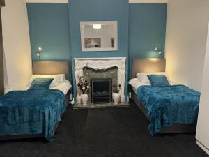 伯明翰Largee 5 Bed House, Sleeps 10 Near NEC, BHX, HS2的配有蓝色墙壁和壁炉的客房内的两张床