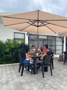 佩德纳莱斯HOTEL PLAYAS PERDERNALES ECUADOR的一群人坐在桌子上,在伞下