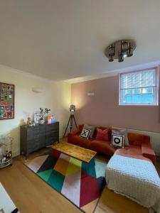 伦敦Chic Victorian Flat in Private Estate - Mile End!的客厅配有沙发和色彩缤纷的地毯