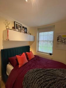 伦敦Chic Victorian Flat in Private Estate - Mile End!的一间卧室配有一张带红色枕头的床和一扇窗户