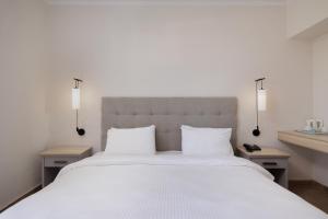 达西亚Nafsika Hotel - Adults Only的卧室配有一张带两张桌子的大型白色床
