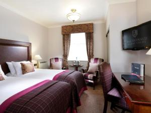 威根麦克唐纳凯利苑酒店& Spa的酒店客房设有一张床、一张书桌和一台电视机。