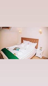 CoruşuSeara pe deal的一间卧室配有一张带白色床单的床和床头柜。