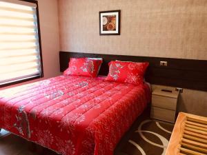 奥索尔诺mirabosque new aparments 2的一间卧室配有一张带红色床单的床和一扇窗户。