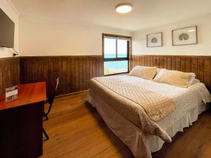 CoronelHotel Bután Coronel的一间卧室配有一张床、一张书桌和一个窗户。