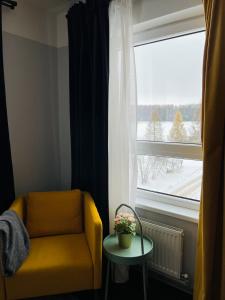 叶卡布皮尔斯Mežaparka apartamenti的黄色椅子和窗前的桌子