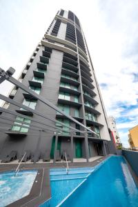 布里斯班Oaks Brisbane on Felix Suites的一座高大的建筑,前面有一个游泳池